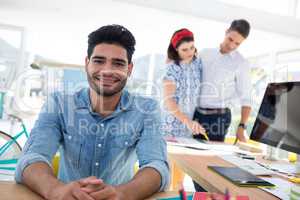 Male graphic designer relaxing while coworkers working in the office