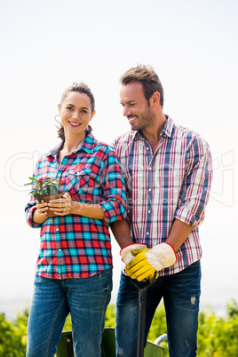 Portrait of beautiful woman with man holding potted plant