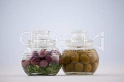 Close up of red and green olives in glass jar