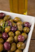 Close up of olives with rosemary served in white bowl