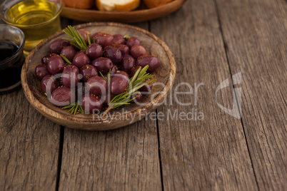 High angle view of olives with herb in wooden plate