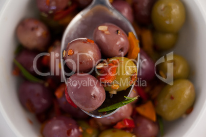 Close up of spoon with olives over container