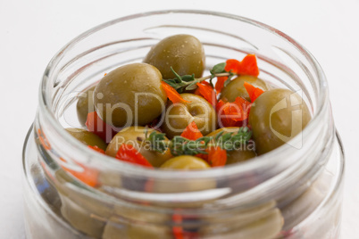 Close up of green olives with herbs in jar