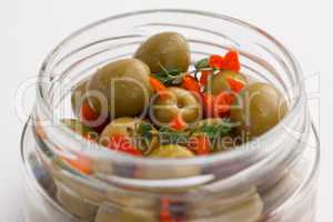 Close up of green olives with herbs in jar