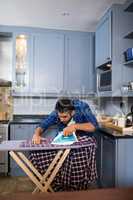 Man ironing shirt while standing in kitchen