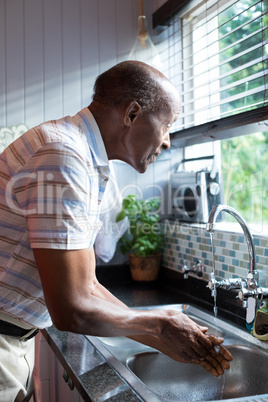 Side view of man looking away while washing hands