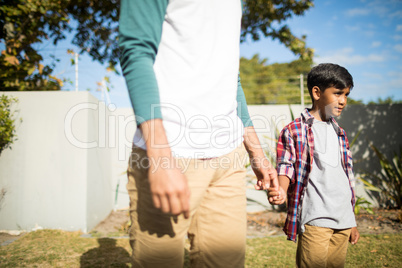 Father and son holding hands during sunny day