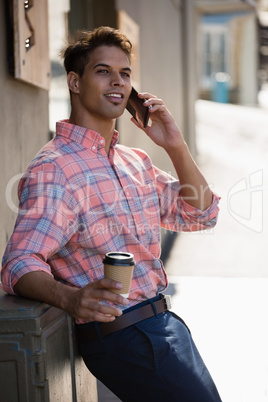 Young man looking away while talking on smart phone