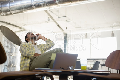 Man looking up while talking on phone in office