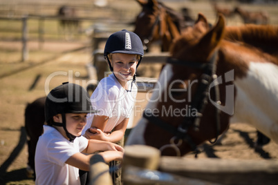 Smiling girls looking at the horse in the ranch