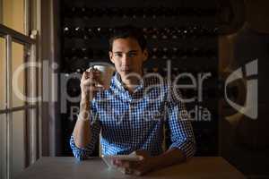 Man holding digital tablet and coffee cup in restaurant