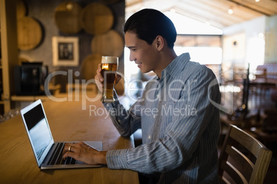 Man using laptop while having beer Man using laptop while having beer