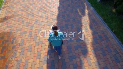 Aerial footage of nurse pushing elderly woman on wheelchair outdoors