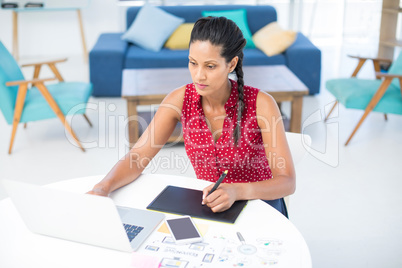 Female graphic designer using graphic tablet at desk