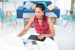 Female graphic designer using graphic tablet at desk