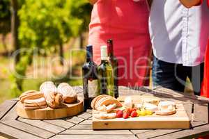 Midsection of friends by food and wine bottles on table