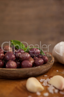 Close up of black olives by garlic on cutting board