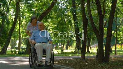 Senior woman pushing husband in wheelchair