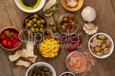 Olives with vegetable and spice by oil in bowl on table