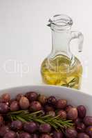 Olives with rosemary in bowl by oil jar