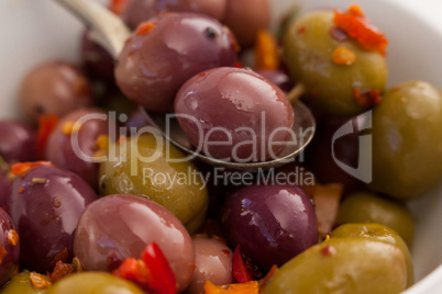 Spoon with olives over bowl