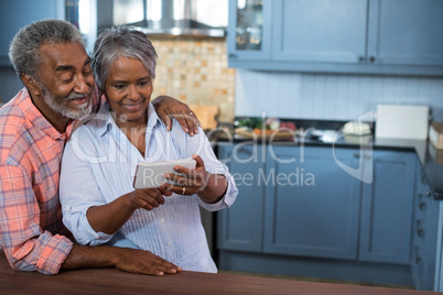 Couple using mobile phone in kitchen