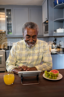 Smiling senior man using tablet computer in kitchen