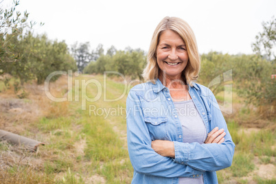 Happy woman standing with arms crossed in olive farm