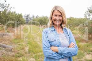 Happy woman standing with arms crossed in olive farm