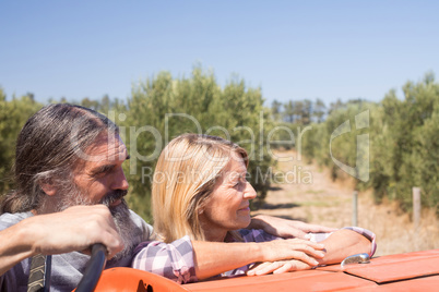Thoughtful couple standing near tractor in olive farm