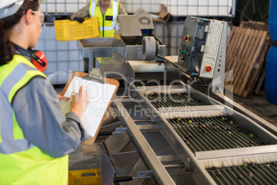 Female technician writing on clipboard