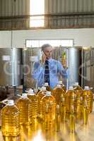 Manager talking on mobile phone while examining olive oil