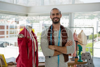 Portrait of designer with arms crossed while standing by mannequin