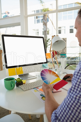 Designer holding color swatch while sitting at desk