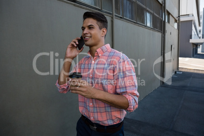 Man talking on mobile phone while walking by wall