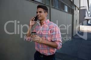 Man talking on mobile phone while walking by wall