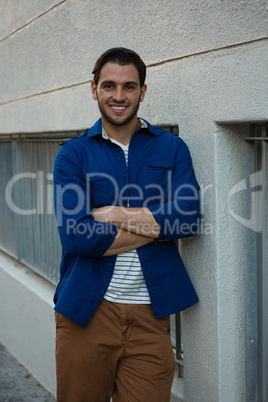 Smiling man with arms crossed leaning on wall