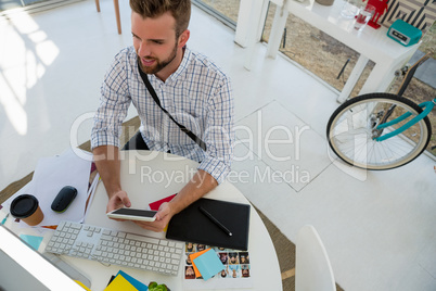 Graphic designer using tablet computer at desk in studio