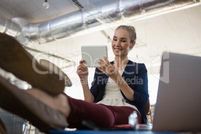 Businesswoman using digital tablet while relaxing at table