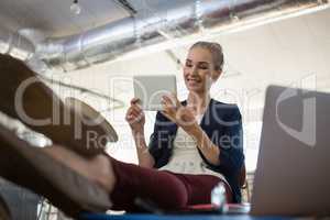 Businesswoman using digital tablet while relaxing at table