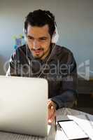 Young man listening to headphones while using laptop