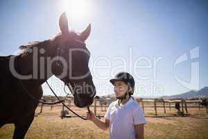Smiling girl standing with the horse in the ranch