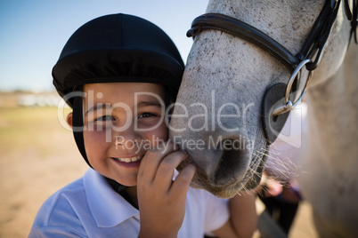 Smiling rider boy touching the white horse