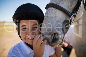 Smiling rider boy touching the white horse
