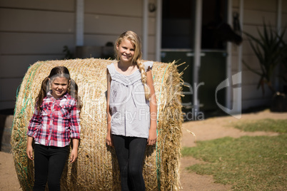 Siblings leaning on hay in the farm