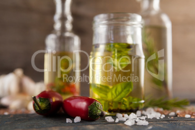 Close up of jalapeno pepper by spices and herbs with oil in containers