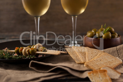 Close up of crackers with olives served in plate by white wine