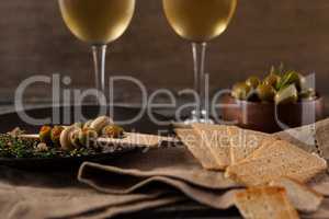 Close up of crackers with olives served in plate by white wine