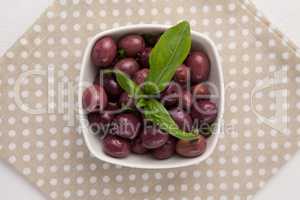 Overhead view of black olives in bowl with herb