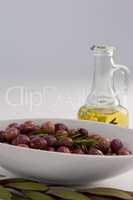 Rosemary with olives in bowl by oil jar